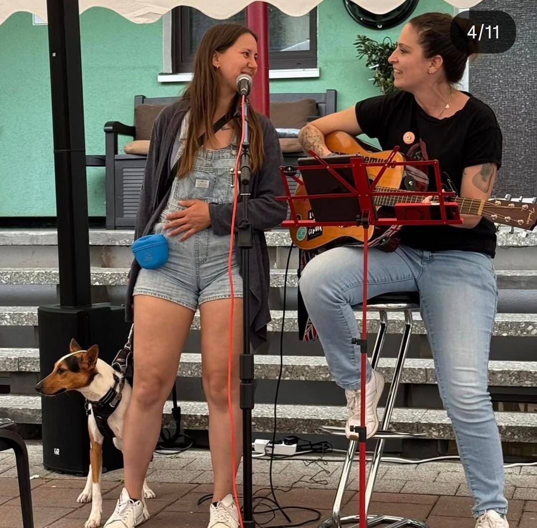 Live-Musik mit Gitarre und Gesang, daneben ein Hund