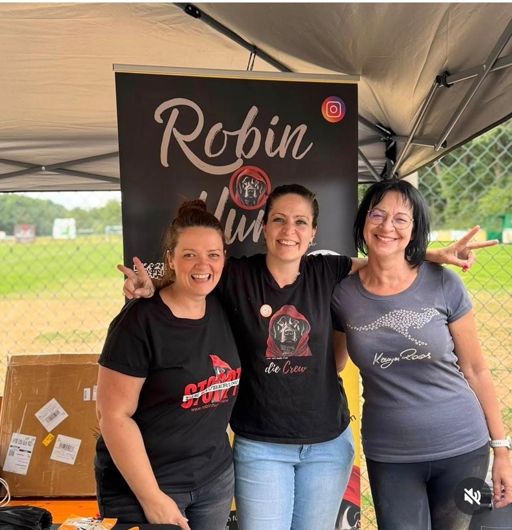 Drei Frauen vom Robin-Hund-Team vor dem Banner am Stand
